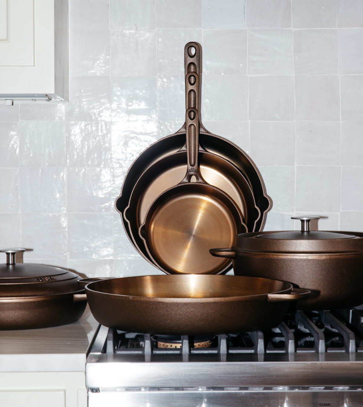 Image of a set of Made In cast iron skillets shown resting against a wall in a bright kitchen.