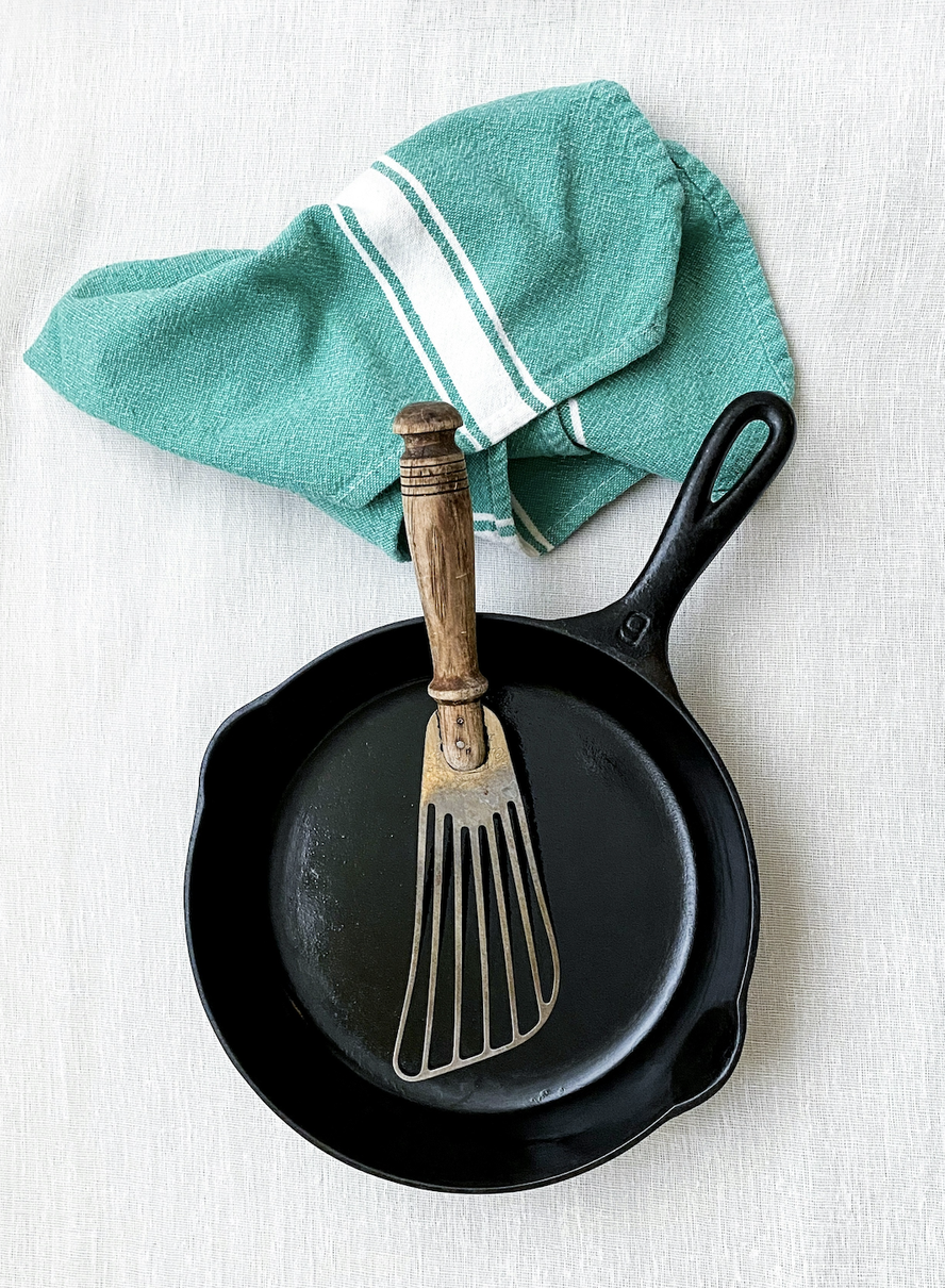 overhead shot of one of the steps in how to clean a cast iron skillet showing the finished product and the towel used